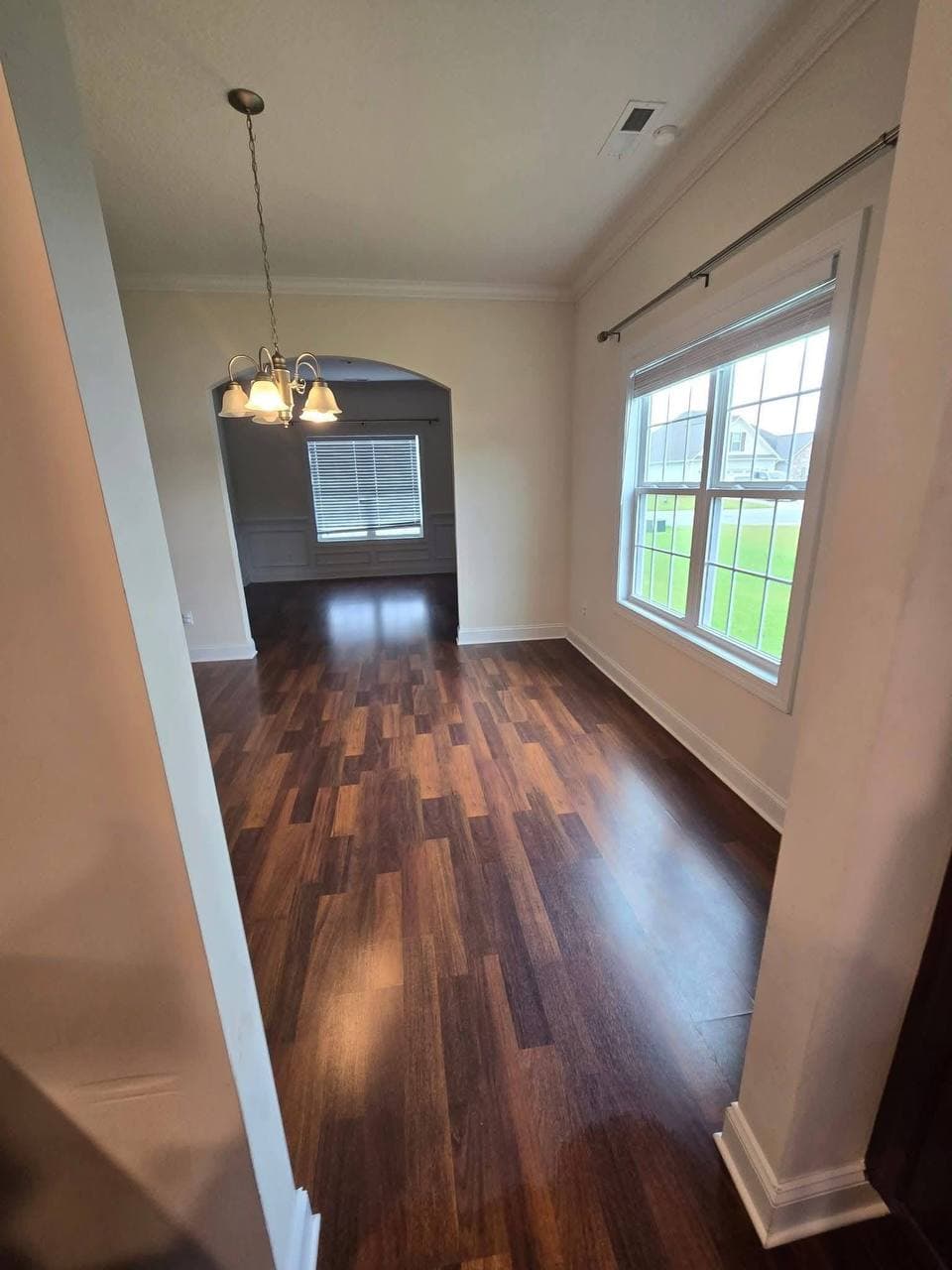 Spotless hallway with hardwood floors and a chandelier